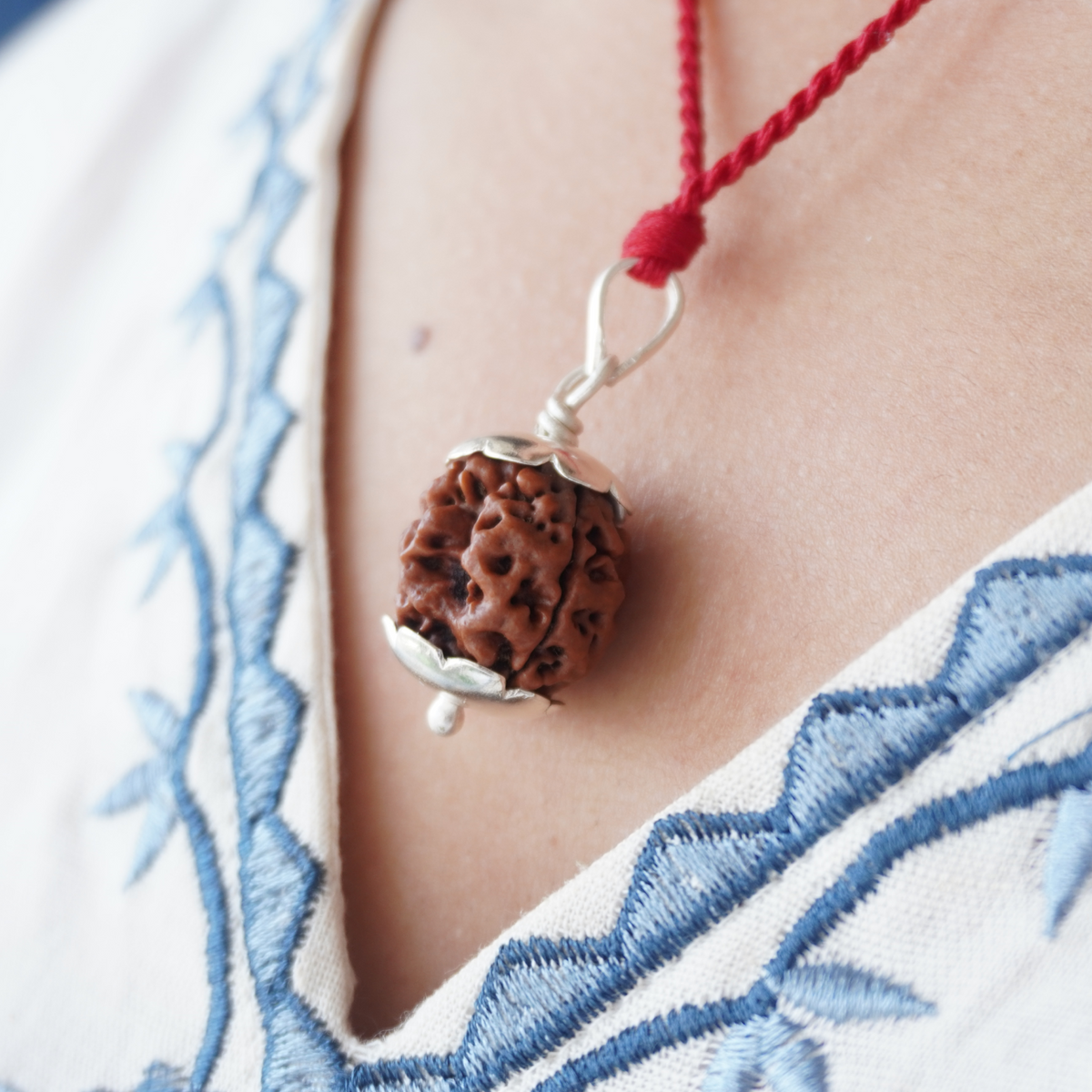 Red Thread 3 Mukhi Rudraksha pendant worn, close up